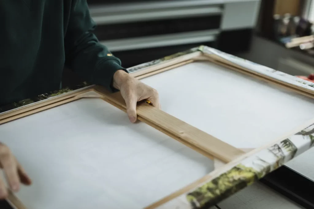 Pose d'une toile sur un châssis en bois à l'atelier d'encadrement Le Cadre