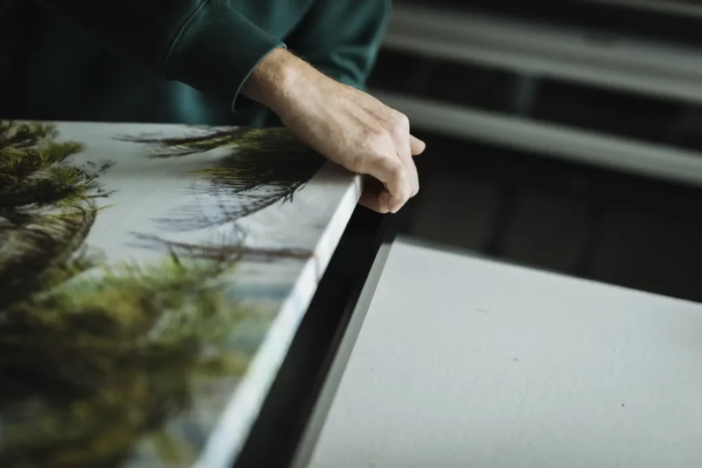 Réalisation de la pose d'une toile sur un châssis en bois à l'atelier d'encadrement Le Cadre